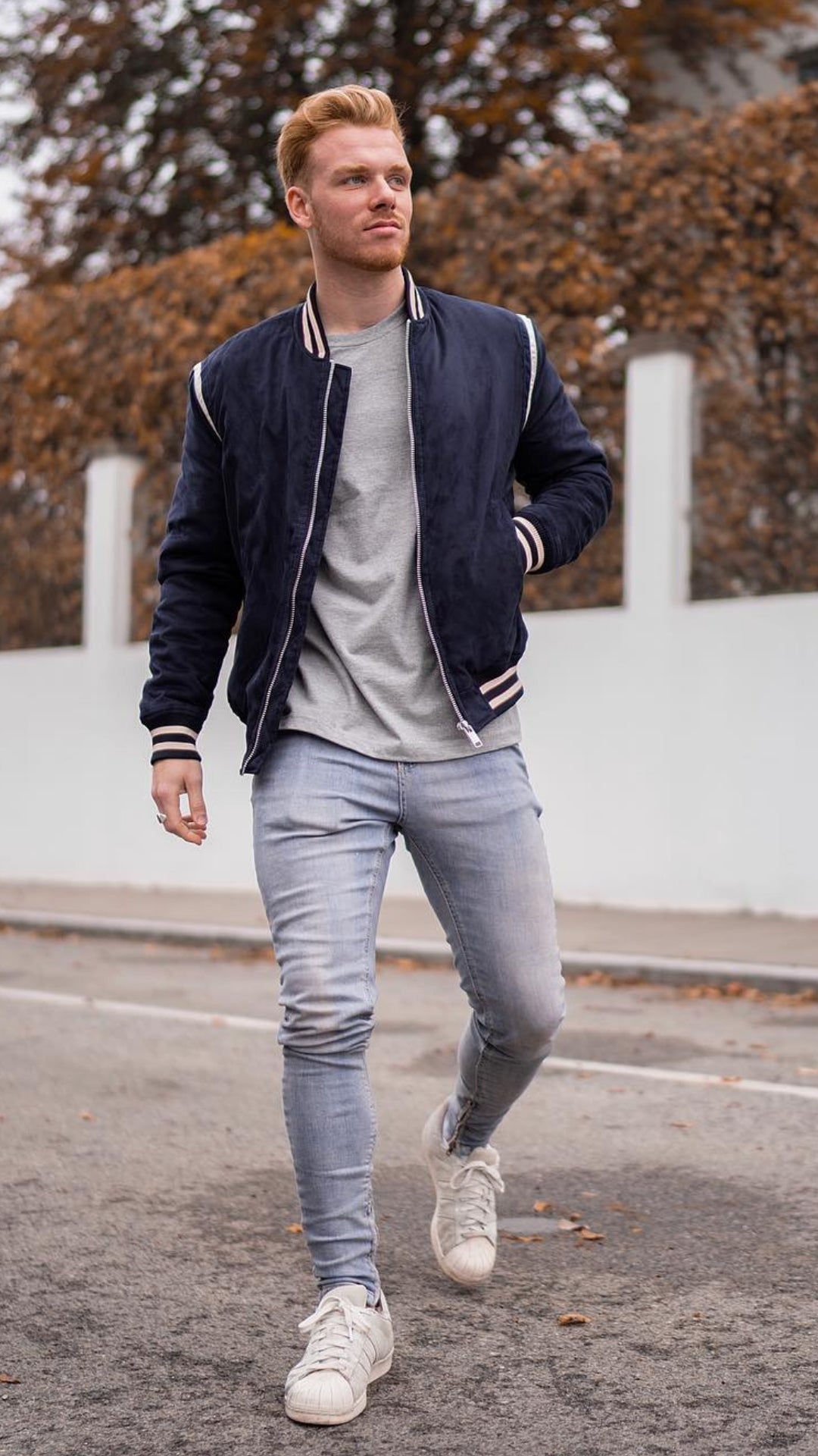 man wearing light blue jeans, grey t-shirt and navy blue bomber jacket