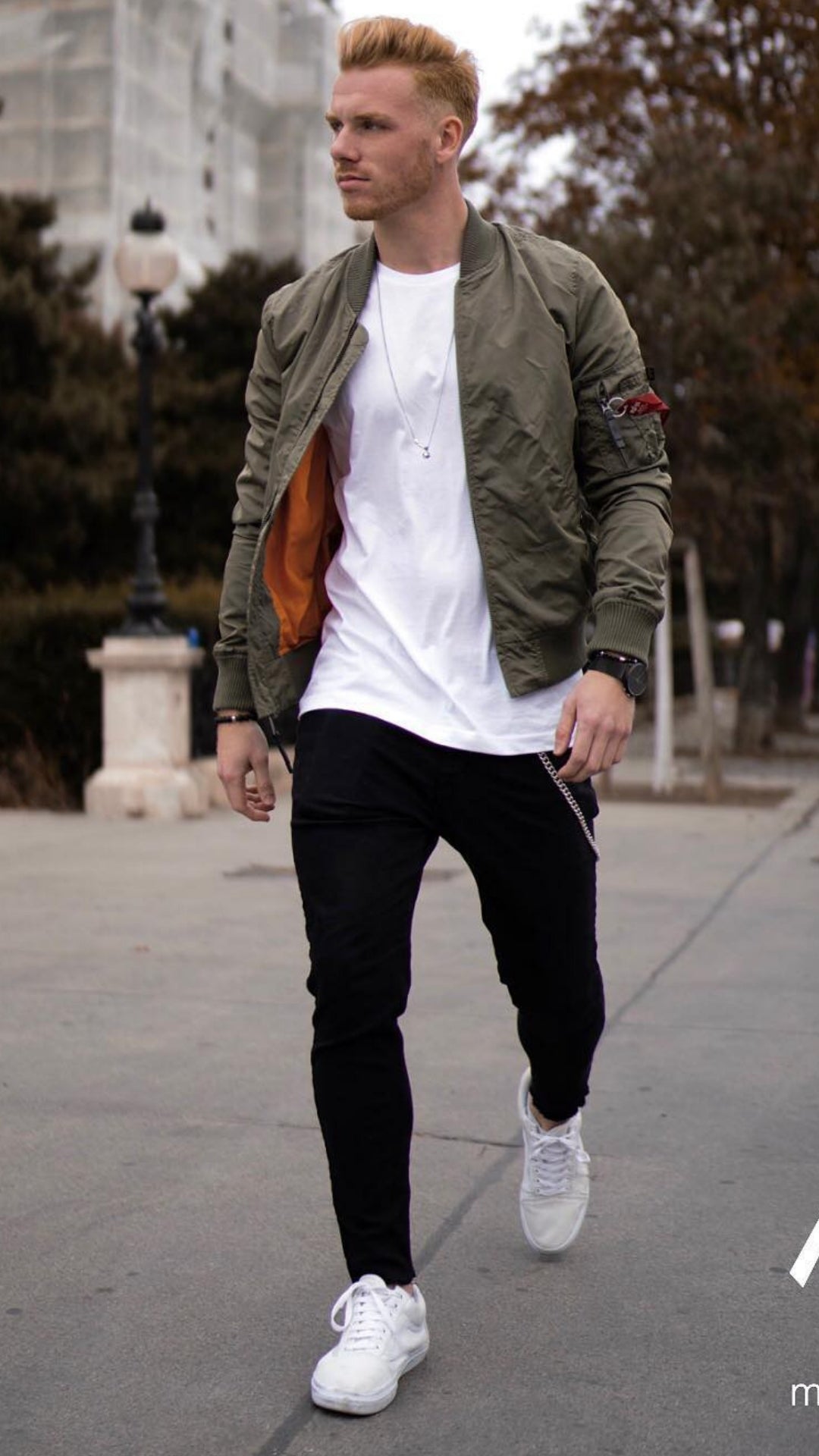 man wearing black jeans, white t-shirt and olive bomber jacket