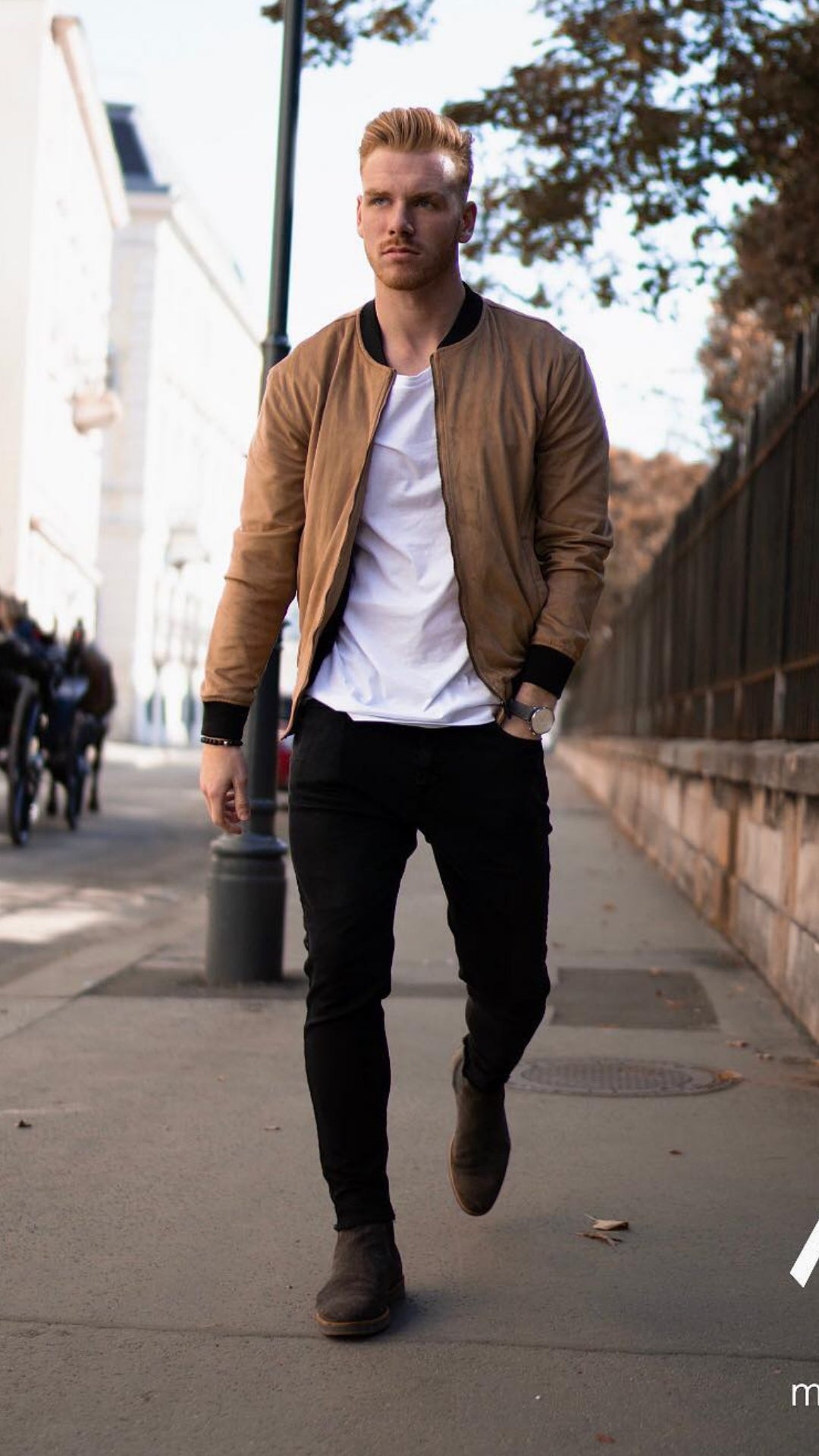 a man wearing black jeans, white t-shirt with camel color bomber jacket